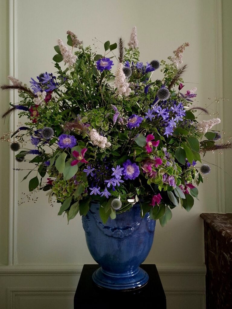 Groot bloemstuk met agapanthus, scabiosa en clematis in een blauwe Anduze-vaas, van Atelier Odiel in Kortrijk.